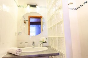 A bathroom with a round mirror, a sink, and a towel on the counter. - Hotel Blanche Neige   (Courchevel)