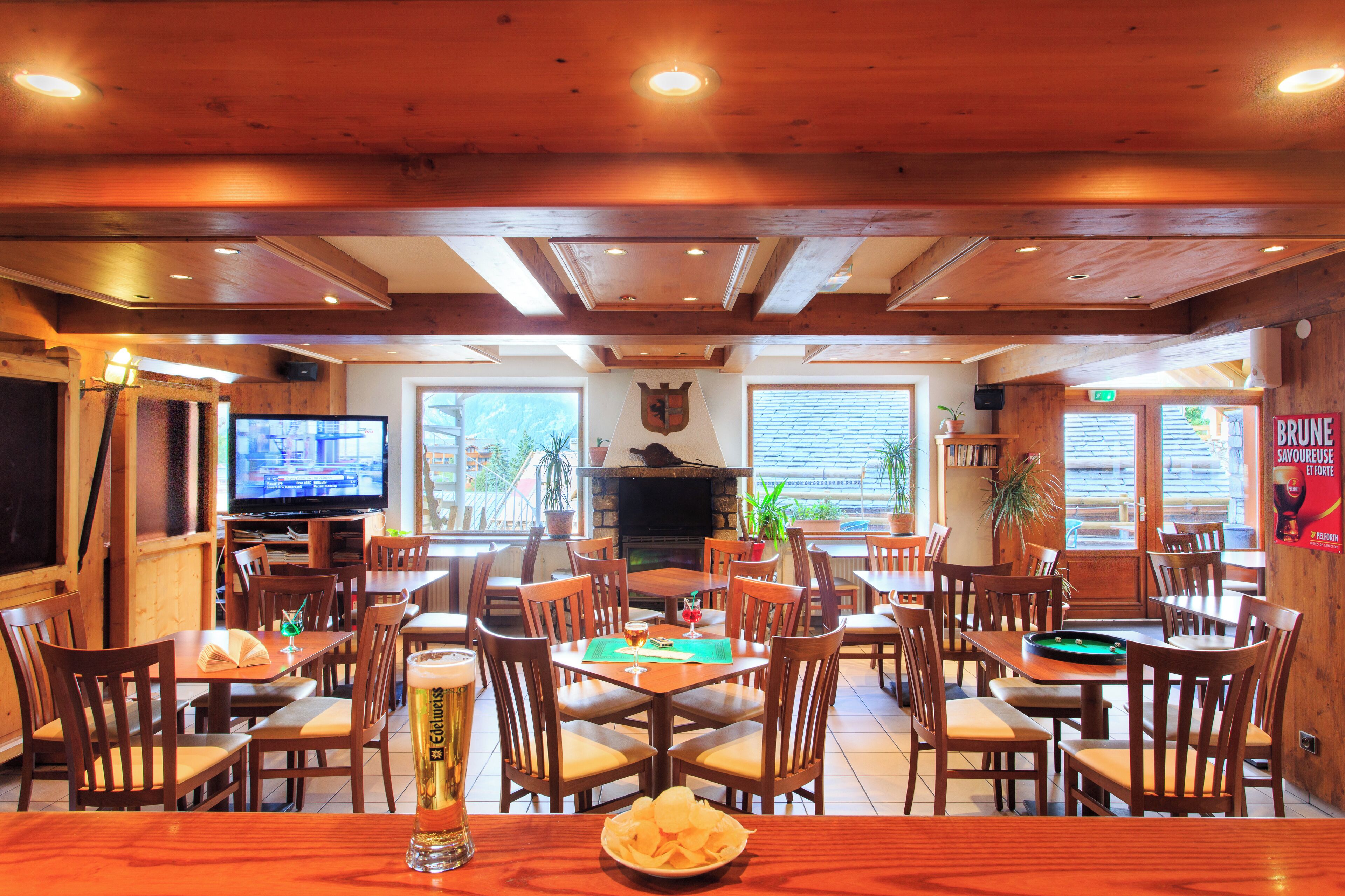 Un restaurante con interiores de madera, varias mesas y sillas, un televisor y una chimenea.