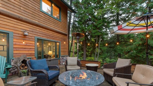 An outdoor patio area with wicker furniture, a fire pit, and string lights.