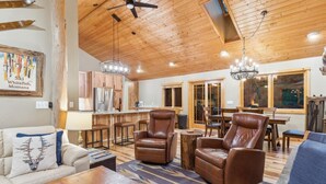 A spacious living room with leather chairs, a wooden coffee table, and a dining area with a large table and chairs.