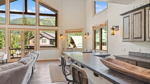A spacious kitchen with large windows, a long counter, and a built-in wooden bar. - Ski-in/Ski-Out with Private Hot Tub (Whitefish)