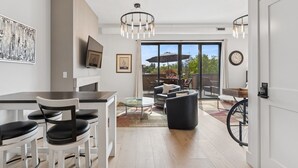 Una sala de estar moderna con comedor, ventanas amplias y espacio accesible para sillas de ruedas.