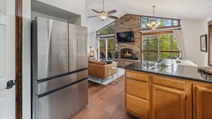 Een moderne keuken met een stenen openhaard, een grote televisie en een eethoek met uitzicht op de omgeving.