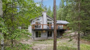 Een chalet met twee verdiepingen en een balkon, omringd door bomen.