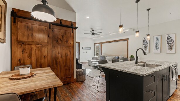 A modern kitchen with a wooden dining table, a large island with a sink, and pendant lighting. - Luxury Condo in Downtown with Fireplace (Whitefish)