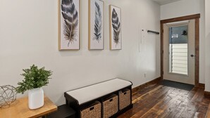 A hallway with three feather artwork on the wall, a bench with baskets, and a door labeled "Suite 202". - Luxury Condo in Downtown with Fireplace (Whitefish)