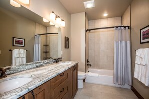 A bathroom with a double sink vanity, a shower, and a toilet. - Private Balcony with Outdoor Fire Table (Whitefish)