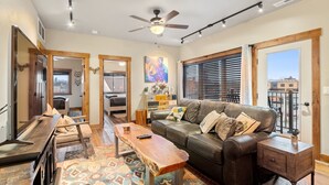 A spacious living room with a leather sofa, a wooden coffee table, and a ceiling fan.