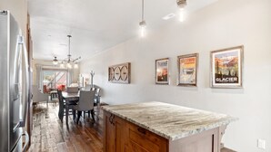 A spacious kitchen with a wooden island, stainless steel appliances, and a dining area with a view. - Penthouse with Hot Tub and Fire Table (Whitefish)
