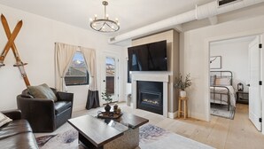 A modern living room with a fireplace, leather sofa, and a mounted TV.