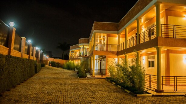 Hotel com vários andares, entrada por um caminho pavimentado e varandas iluminadas.