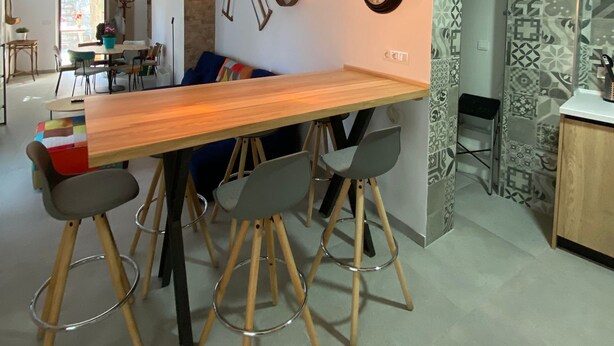 Una cocina moderna con una isla de madera, luces colgantes y relojes decorativos en la pared.