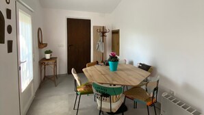 Un comedor con una mesa y sillas de madera, una planta en maceta y una viga en el techo.
