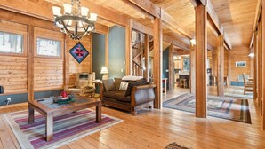A spacious wooden interior with a chandelier, a sofa, a coffee table, and a dining area. - 5 Mins to Whitefish Resort and Amenities (Whitefish)