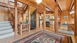 A spacious wooden cabin interior with a staircase, a kitchen, and a dining area. - 5 Mins to Whitefish Resort and Amenities (Whitefish)