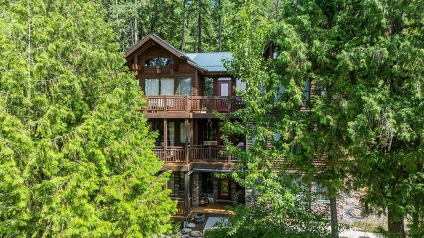A two-story log cabin with a balcony, surrounded by dense forest. - 5 Mins to Whitefish Resort and Amenities (Whitefish)