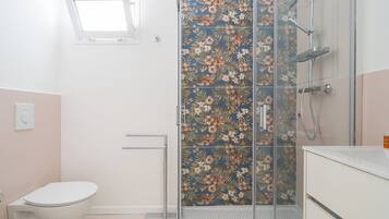 A bathroom with a shower, toilet, and a window.
