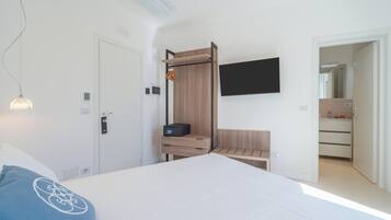 Une chambre à coucher moderne avec un lit, un téléviseur fixé au mur, une armoire en bois et un bureau avec une lampe.