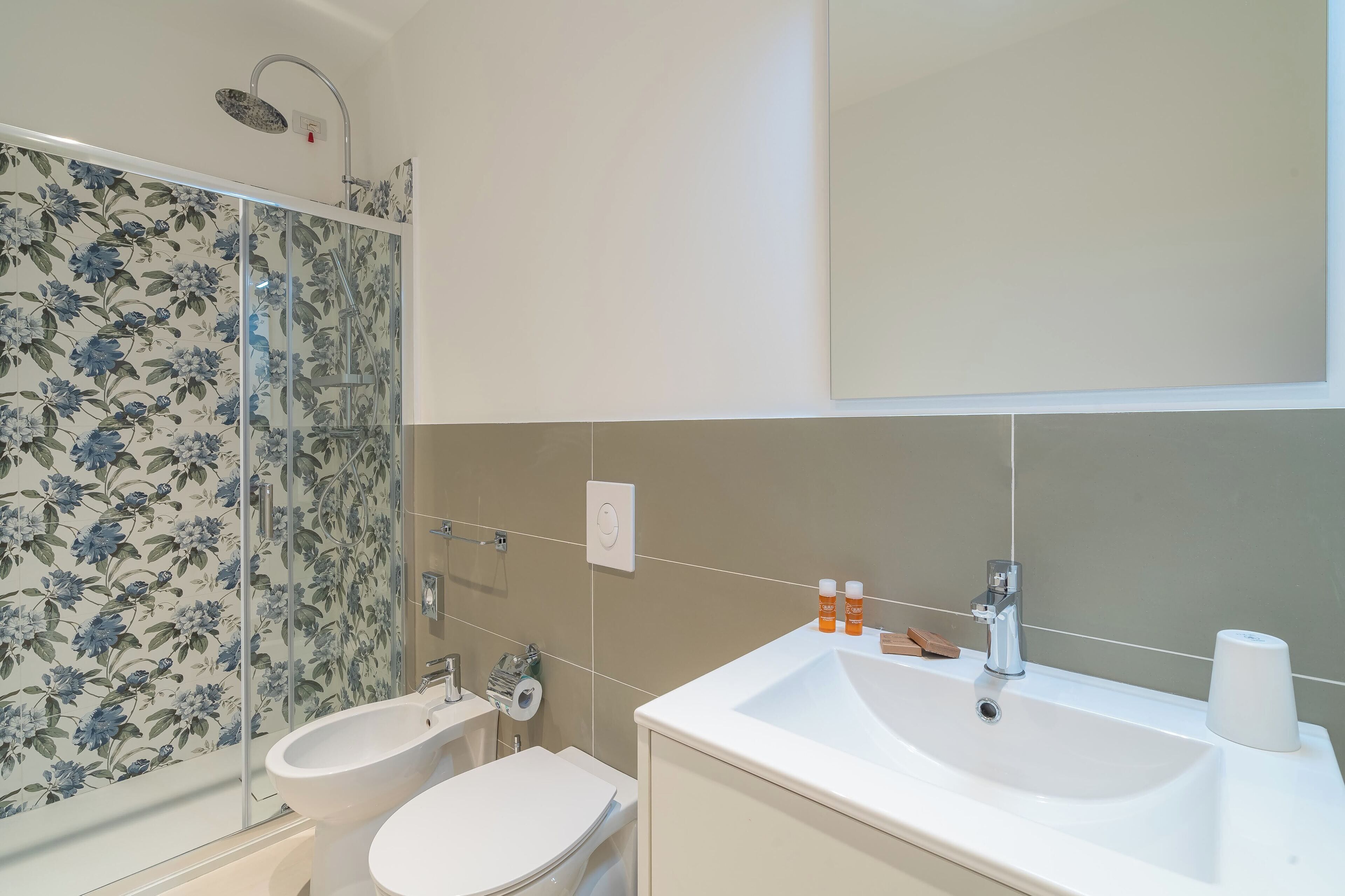 A bathroom with a shower, bidet, toilet, and sink.