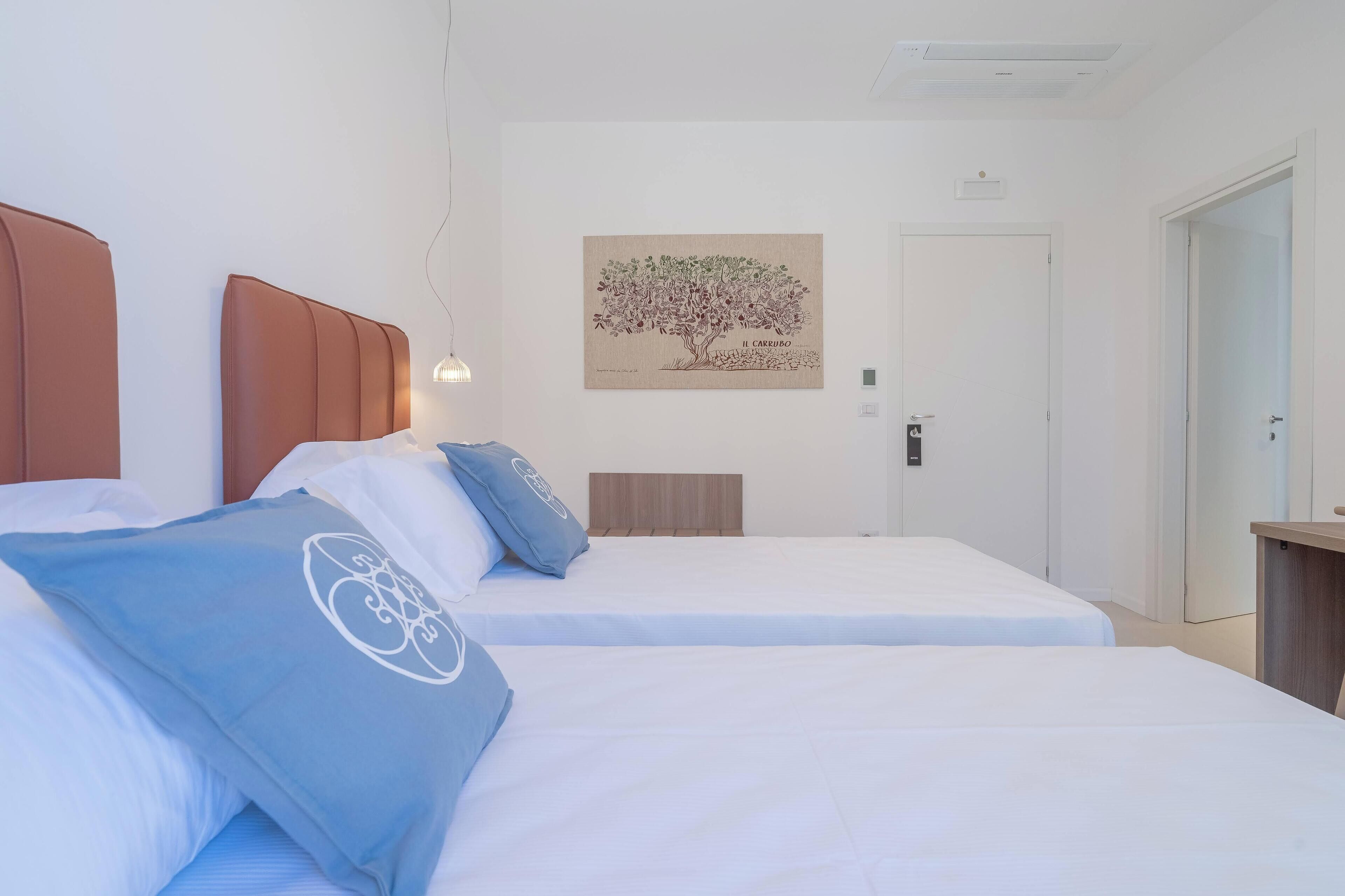A hotel room with two beds, a wall-mounted artwork, and a door.