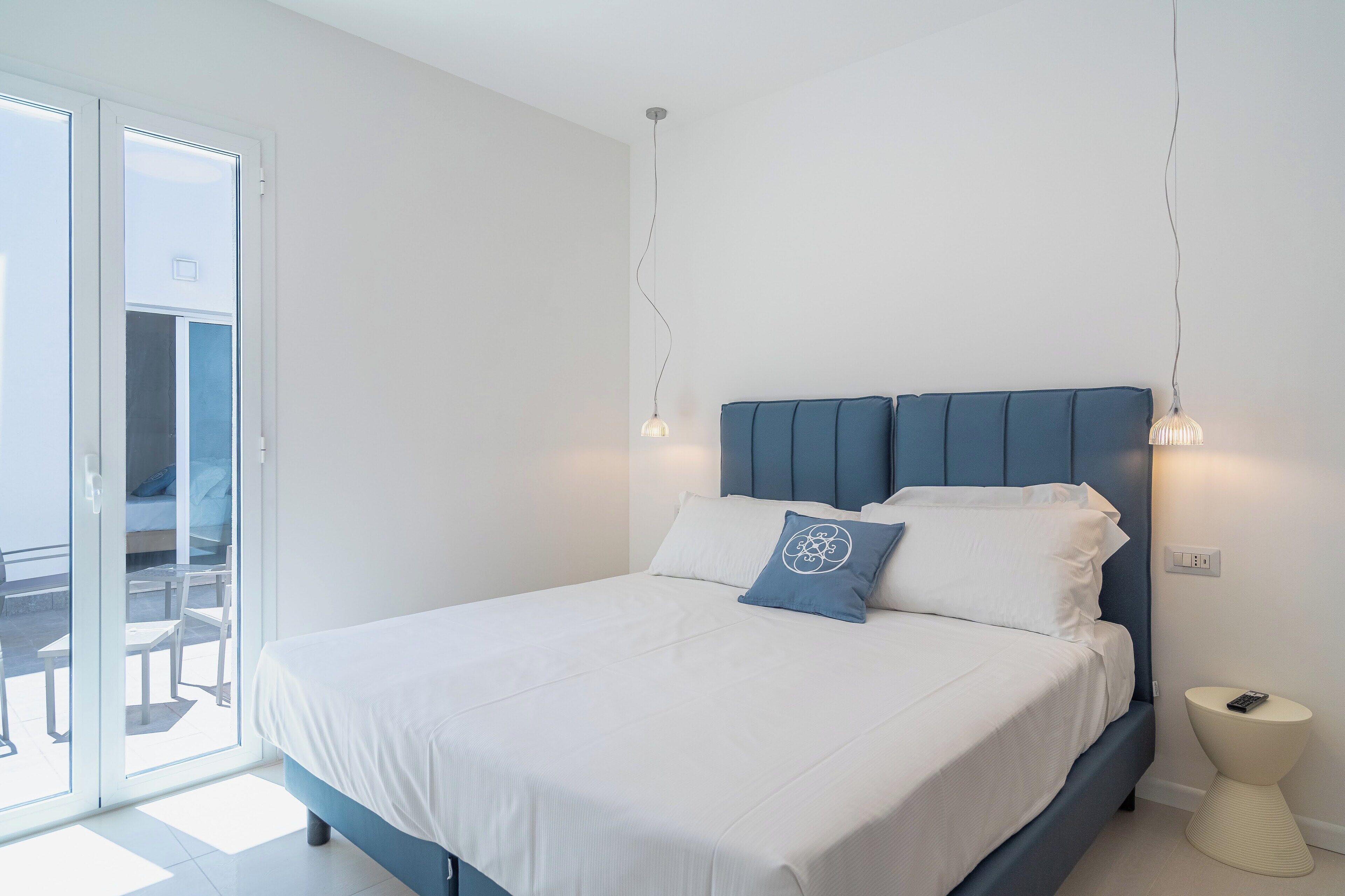 Une chambre à coucher comprenant un lit, une table de chevet et une vue sur l’extérieur, accessible par une porte coulissante.