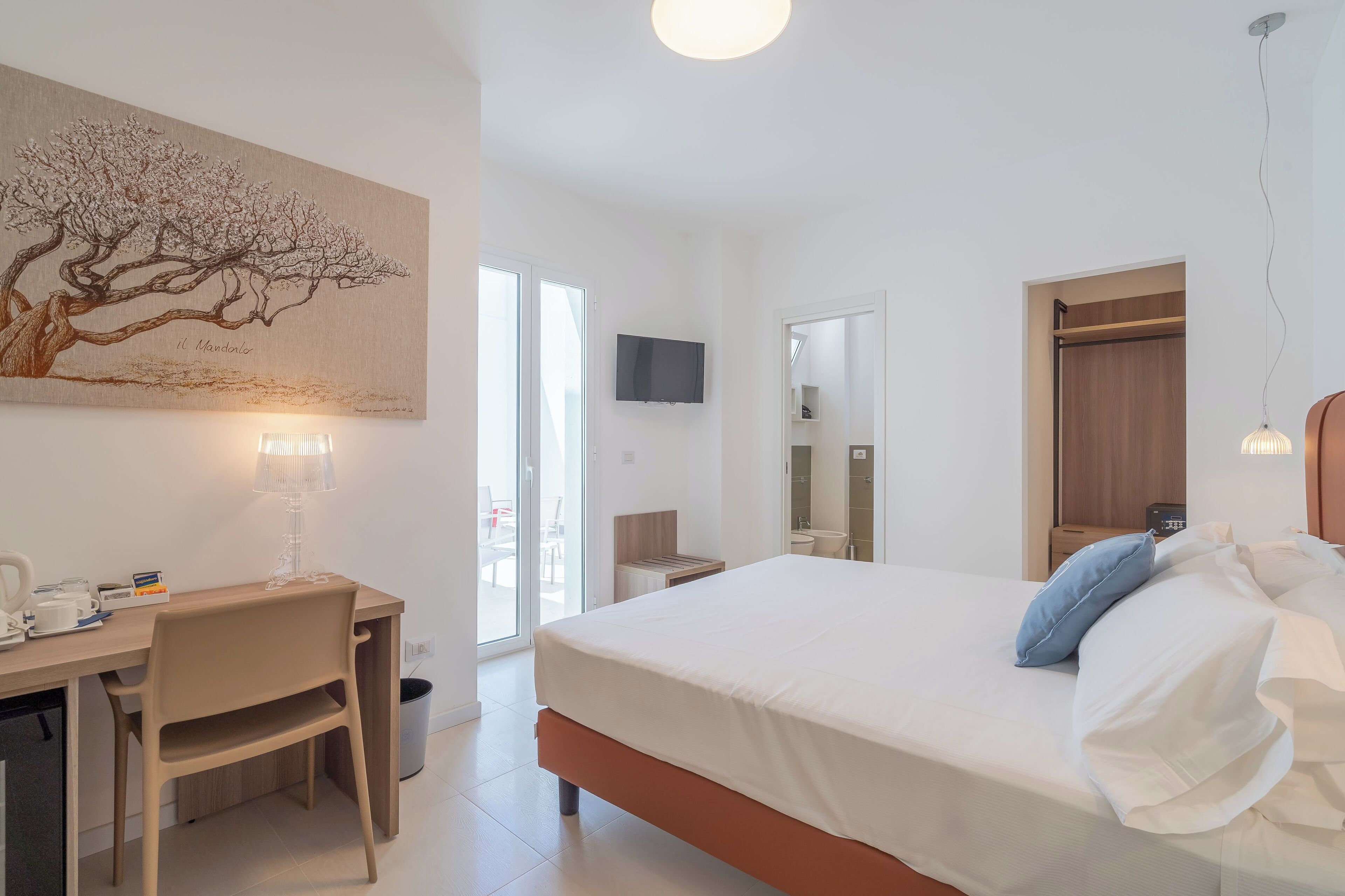 A modern bedroom with a bed, desk, chair, and a painting on the wall.