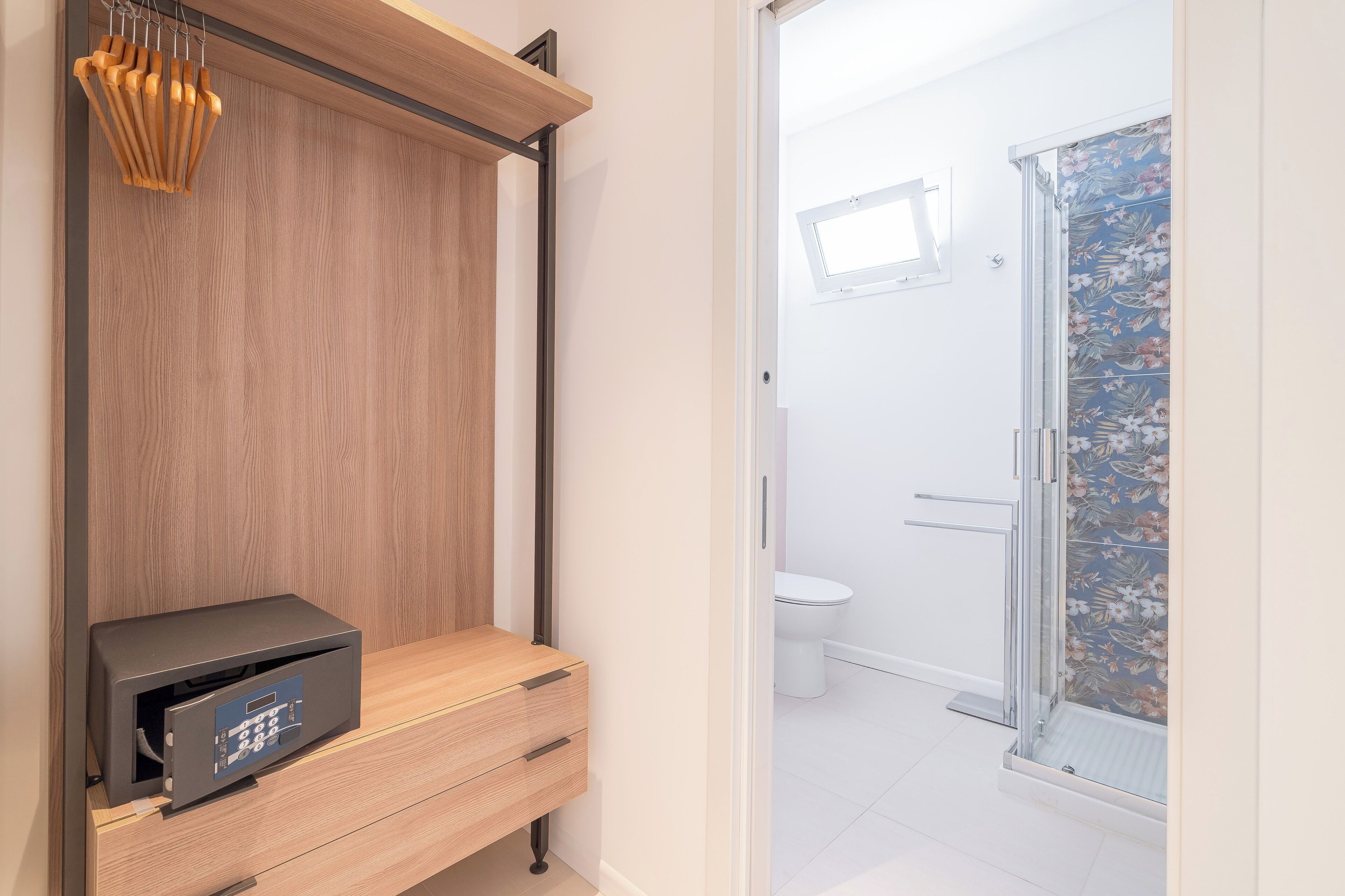 A modern bathroom with a shower, toilet, and a wooden vanity with a built-in charging station.