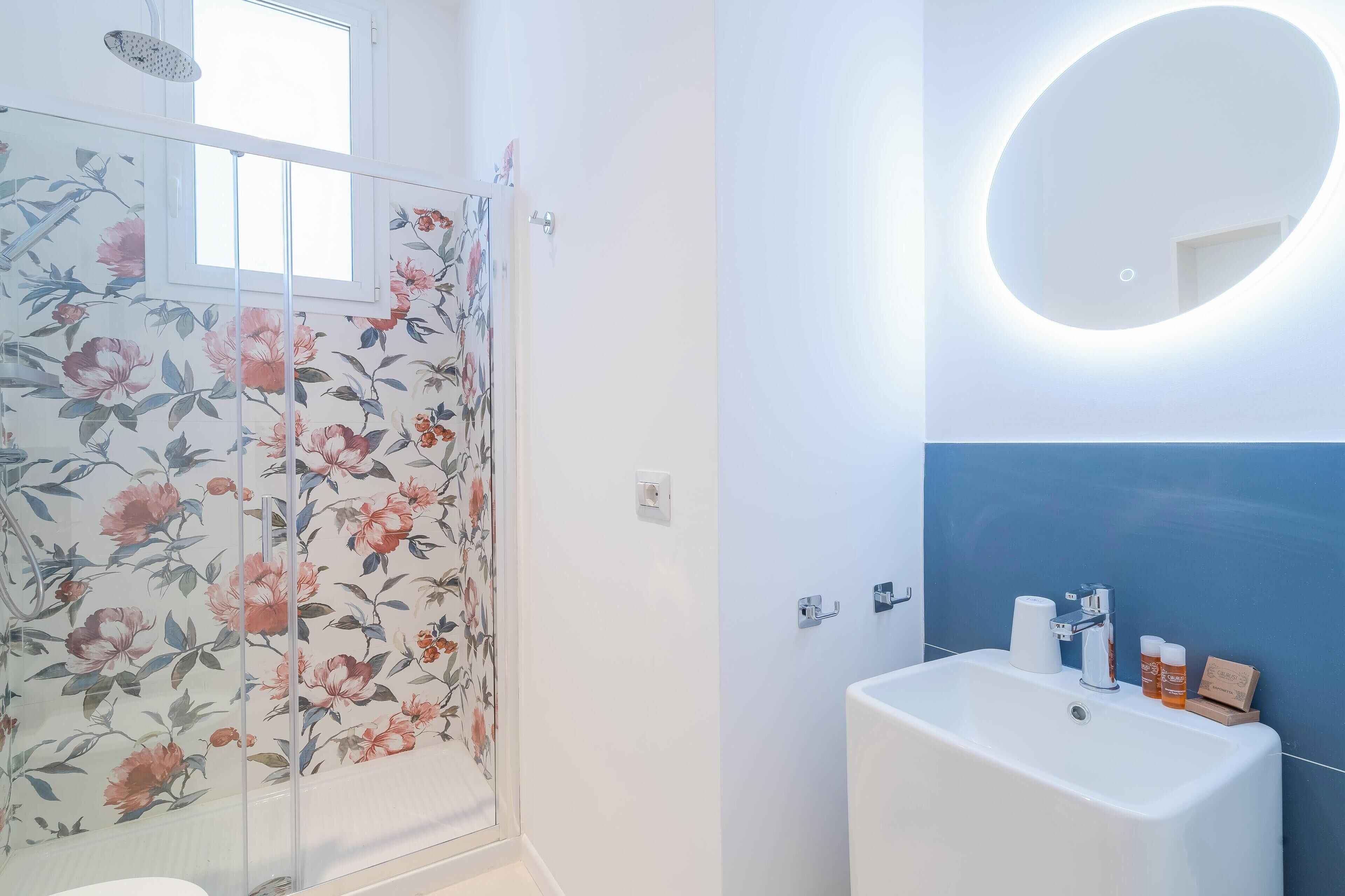 Un baño con ducha, lavabo y espejo.