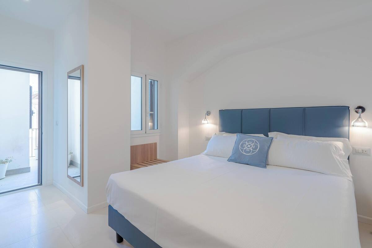 Ein modernes Schlafzimmer mit einem großen Bett, einem blauen Kopfteil und einem großen Spiegel.