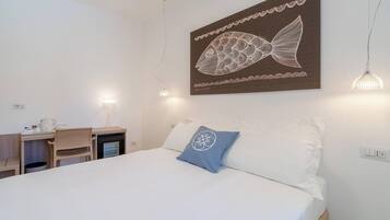Ein Schlafzimmer mit einem Bett, einem Schreibtisch und einem an der Wand befestigten Bild von einem Fisch.