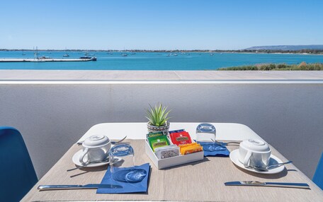 A table set for two with a view of the sea and boats in the background.