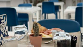 Una mesa con croissants y un cactus, un plato con comida, y vista al mar.