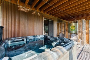 Un bain à remous dans un chalet en bois, avec un plafond et des murs en bois, et une porte donnant sur une autre pièce.