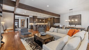A spacious living room with a large sofa, a coffee table, and a dining area with a wooden table and chairs.