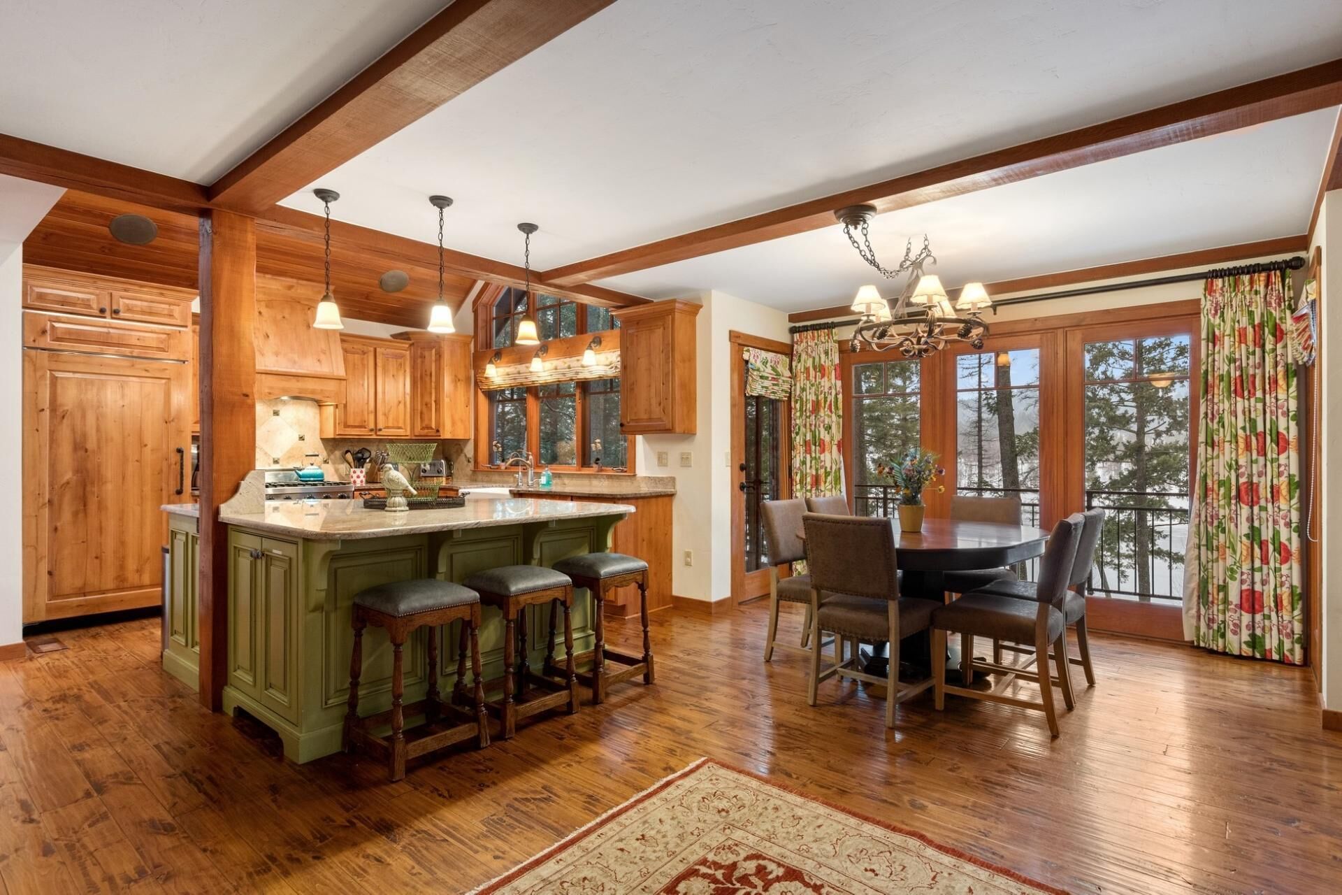 A spacious kitchen with wooden cabinets, a central island with bar stools, and a dining area with a chandelier.