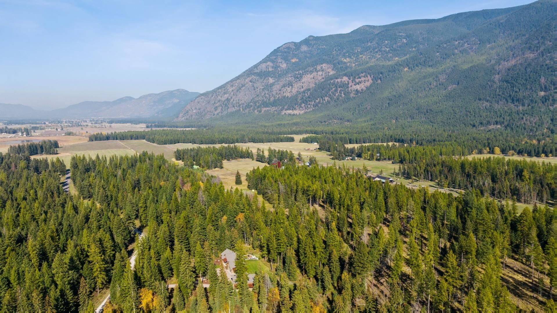 Een bergachtig landschap met dichte bossen en verspreide gebouwen.