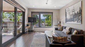 A modern living room with a large window, a flat-screen TV, a sofa, and a coffee table.