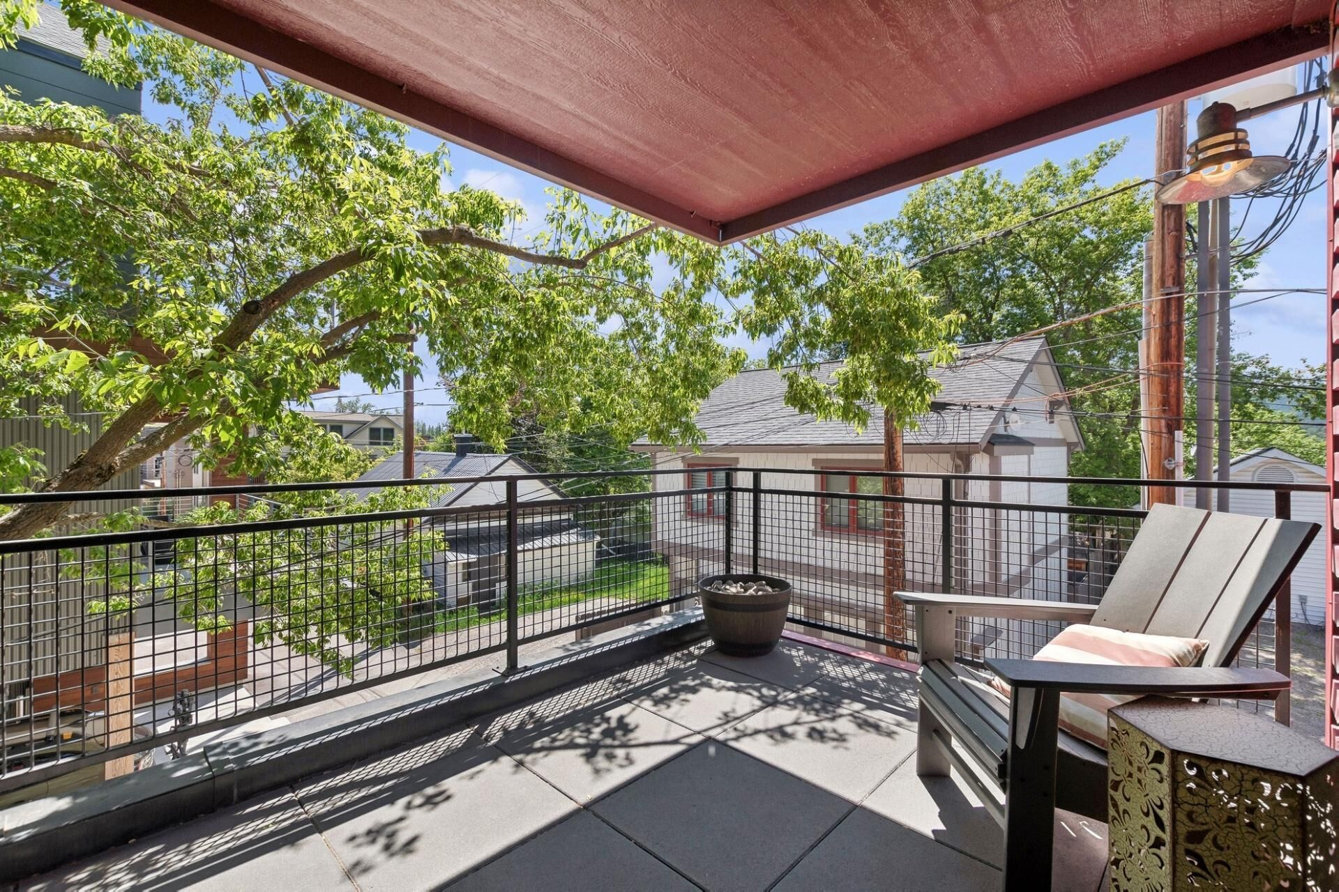 A balcony with a metal railing, a chair, and a table.
