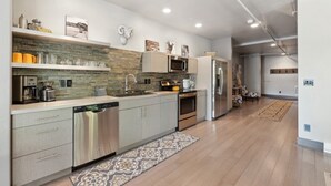 A modern kitchen with a central island, stainless steel appliances, and a backsplash of textured tiles.