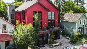 A red building with the number 22 on its facade, surrounded by greenery and other buildings.