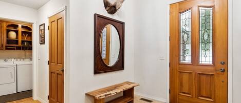 Un pasillo con un banco de madera, un espejo y una cabeza de venado montada en la pared.