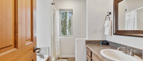 A bathroom with a wooden vanity, a large mirror, and a window providing natural light.
