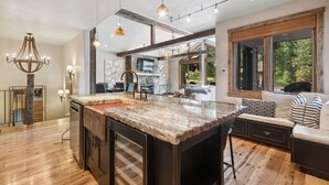 A spacious kitchen with a large island, wooden flooring, and a view of the outdoors. - Ski-in/Ski-out Access and Private Hot Tub (Whitefish)