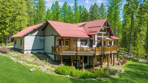 A two-story cabin with a red roof, a balcony, and a deck.