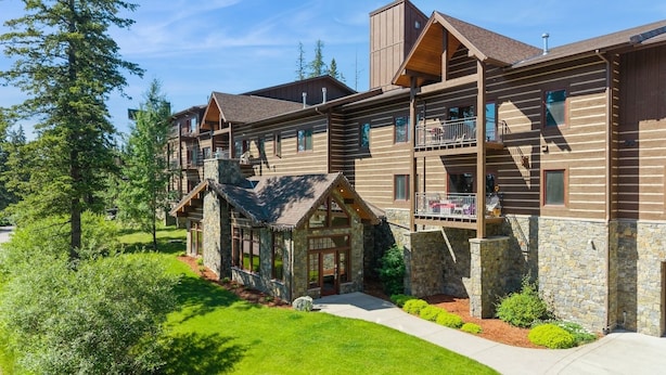 A multi-story log cabin with stone accents, balconies, and a stone entrance.
