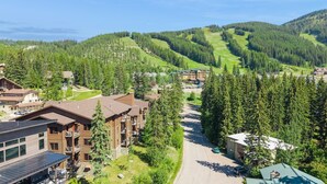 A lodge with a ski slope in the background, surrounded by dense forest.