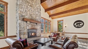 A cozy interior with a stone fireplace, leather furniture, and large windows.