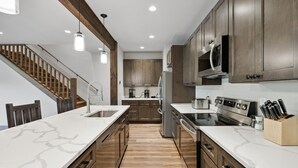 A modern kitchen with wooden cabinets, a marble countertop, and stainless steel appliances.