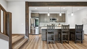 A modern kitchen with a central island, stainless steel appliances, and wooden flooring.