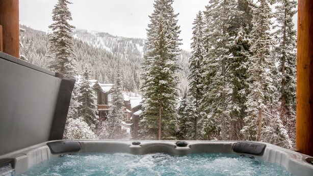 Ein Whirlpool mit Blick auf schneebedeckte Bäume und Gebäude.